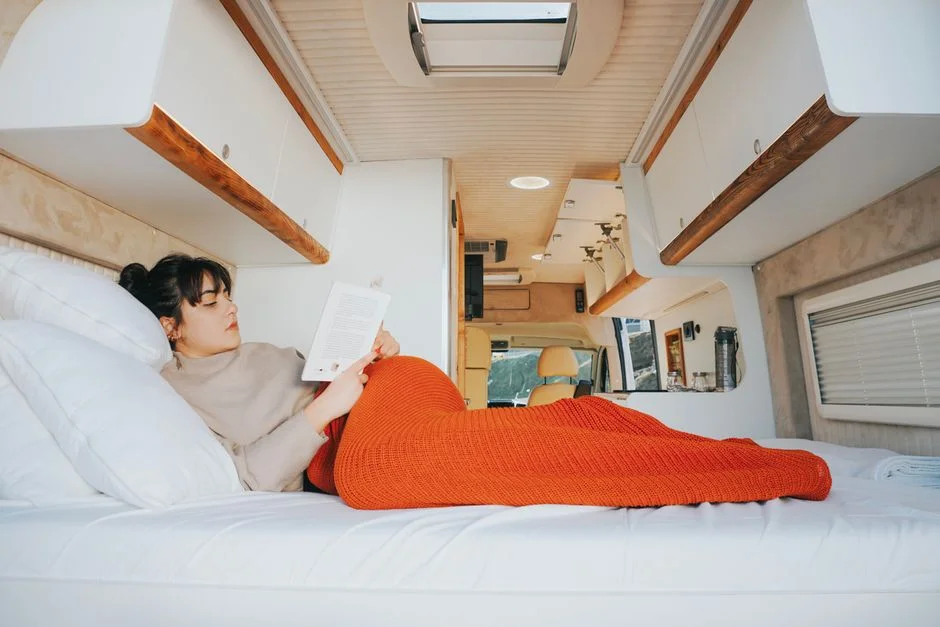 Schlafplatz im Camper-Van mit warmer Decke, entspanntes Lesen im Bett