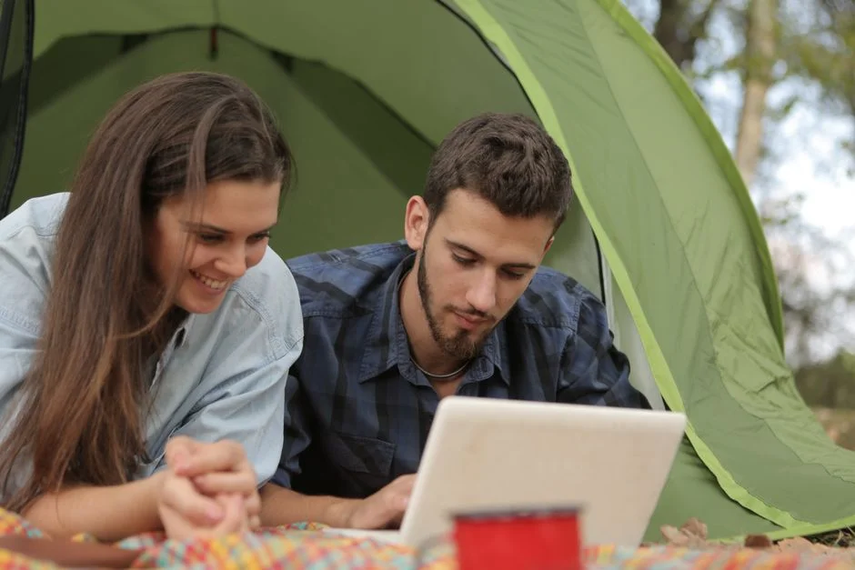 Paar entspannt mit Laptop im Zelt auf dem Campingplatz