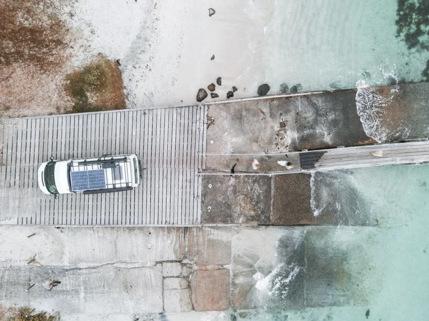 Fahrzeug mit Solarmodulen auf dem Dach aus der Vogelperspektive an der Küste