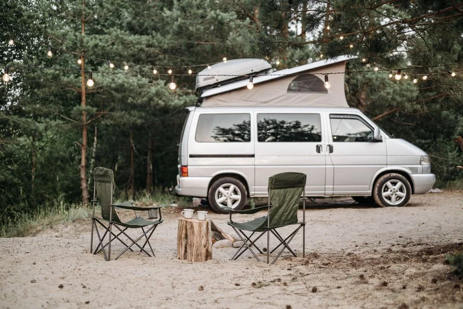 Weißer Camper-Van in natürlicher Umgebung zwischen Bäumen