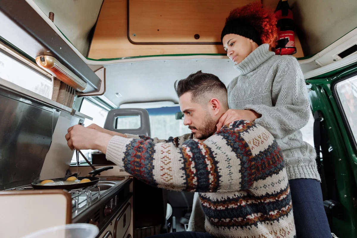 Paar bereitet in der Kompaktküche des Campingvans gemeinsam das Frühstück zu