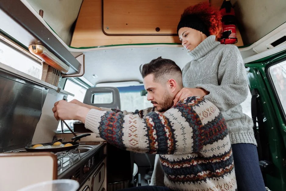 Paar bereitet gemeinsam Essen an der Kochstelle im Camper-Innenraum zu