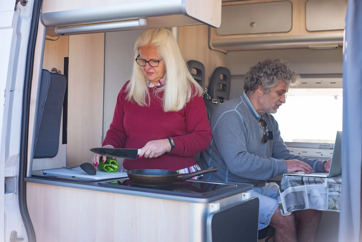 Paar kocht und arbeitet in der hellen Küchenzeile eines Campingvan-Innenausbaus